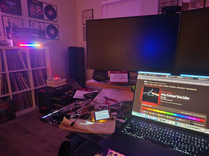 Dark Side of the Moon playing: the stand’s LED strip and the console both showing the rainbow, with the 2-inch cover screen on the desk